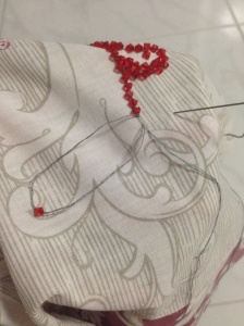 Outlining the flower pattern on the fabric with red beads.